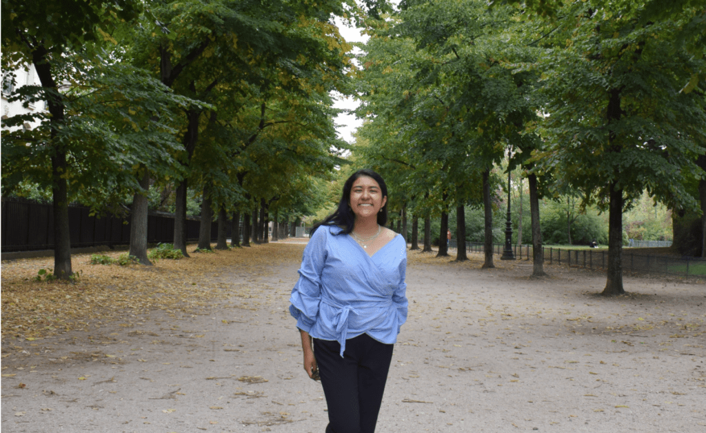Sara C., Xpeer de Nu Colombia, posa sonriendo en una calle arbolada.