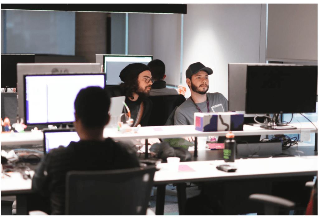 Dos ingenieros jóvenes con gorro en Nu miran atentamente una pantalla.