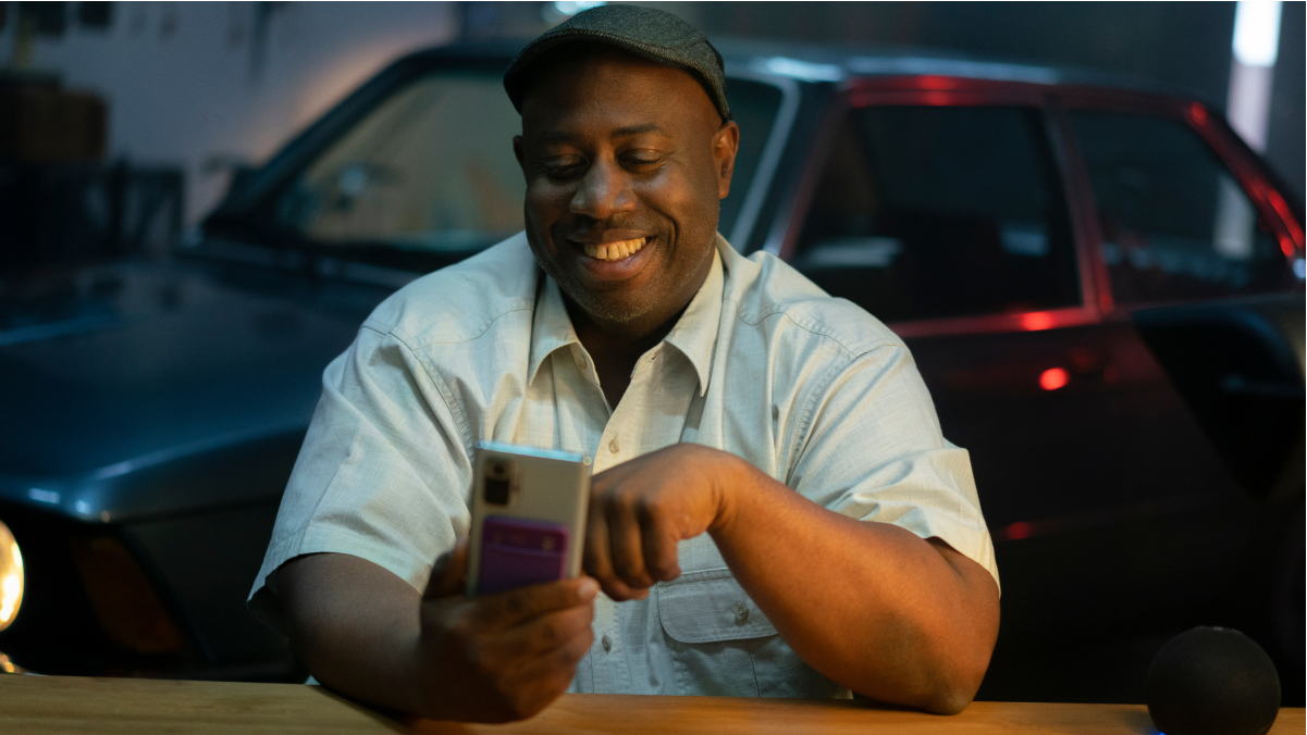 Foto de persona con el celular sonriendo. Vive más con Nu: ¿qué significa sin filas ni asteriscos?