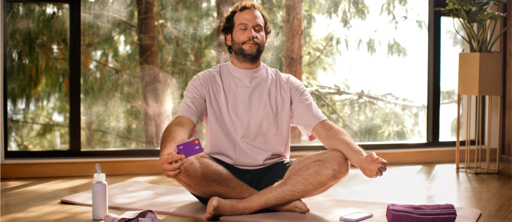 Vive más con Nu: ¿qué significa sin filas ni asteriscos? Foto de hombre meditando con la tarjeta de crédito Nu. Descubre cómo Santiago expandió sus límites.