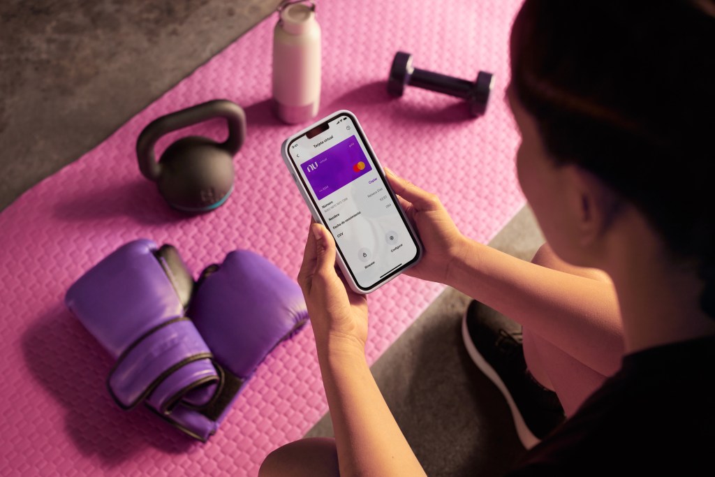 Foto de mujer en su celular viendo la tarjeta virtual de Nu. ¿Por qué dan una tarjeta virtual?