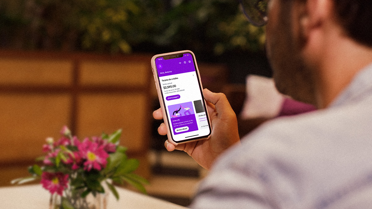 Foto de un cliente con un celular en la mano con el app de Nu abierta