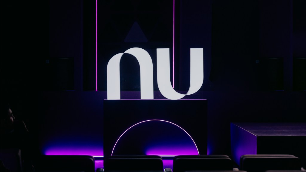 Nu Colombia recibió la aprobación para operar una Compañía de Financiamiento foto de un escenario con algunas luces moradas abajo y en el dentro un logo de Nu en color blanco
