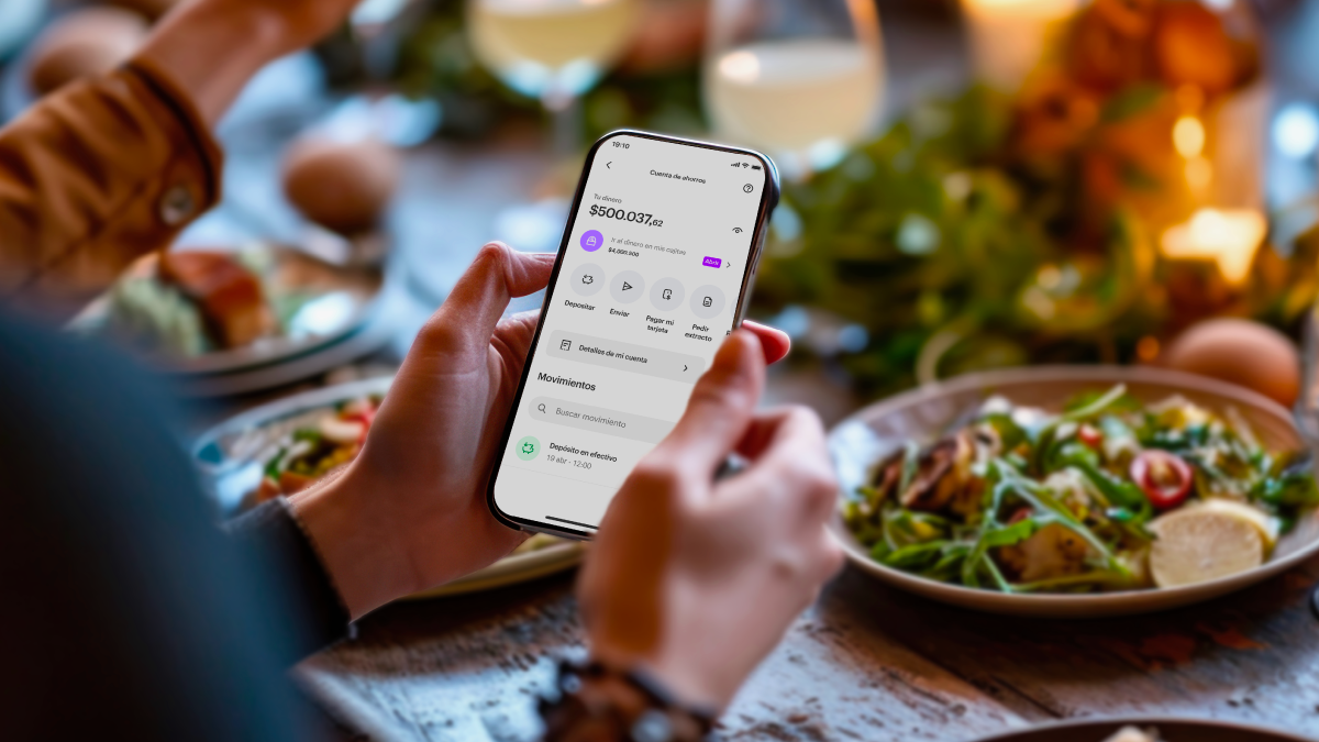 Foto de persona en restaurante viendo su Cuenta Nu. Cena con amigos: ¿Cómo pagar con la Cuenta Nu?